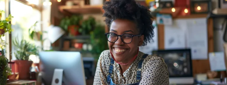 A woman with glasses smiles at the camera while using her laptop, representing an eFax alternative.